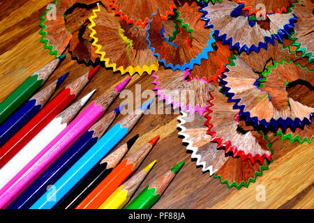 Color pencils and their shavings on a wooden board. Stock Photo