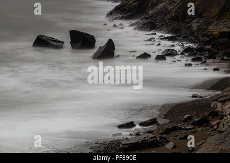 Blurred waves on a rocky beach at Porth Ysgo, North Wales Stock Photo