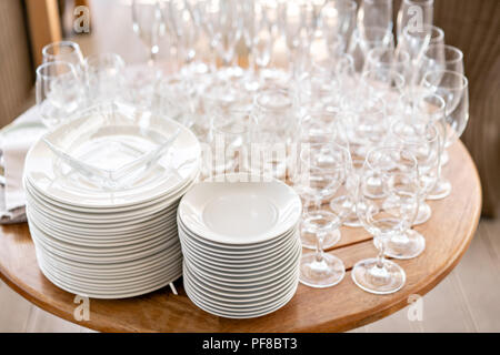 Clean plates, glasses and cutlery on wooden table. Catering set-up ready for the event to begin. ervice area the waiter in restaurant. Stock Photo