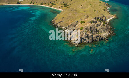 Drone photo looking down on a rocky headland, blue water, and coral reef at Gili Lawa Laut island in Komodo National Park, Indonesia Stock Photo