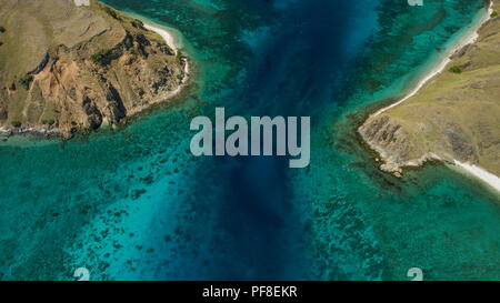 Drone photo looking down on 2 headlands, narrow strait, blue water, shallow coral reef, at the dive site Shotgun aka Cauldron, in Komodo NP, Indonesia Stock Photo