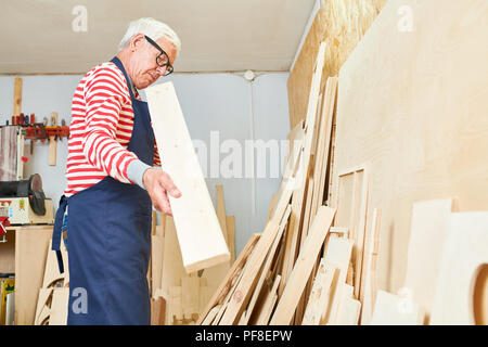 Aged carpenter looking at wooden plank Stock Photo