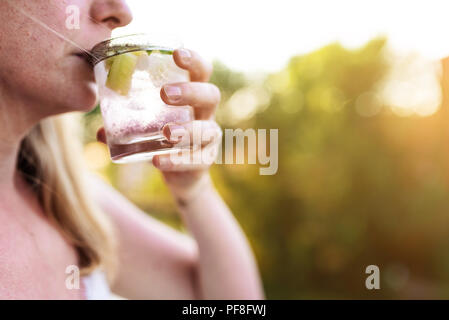 blond woman outdoors drinking iced drink Stock Photo