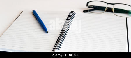 Notebook and glasses and red pen on table. White background Stock Photo