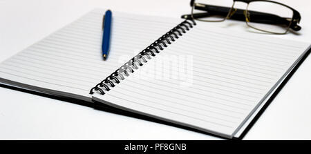 Notebook and glasses and red pen on table. White background Stock Photo