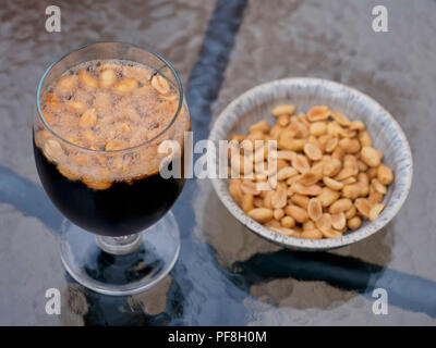 The latest nutty drink craze drinking Coca-Cola / Pepsi Cola with roasted salted peanuts Stock Photo