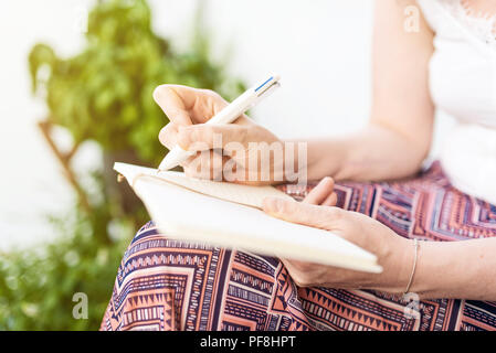 woman sitting on patio taking notes in notebook Stock Photo