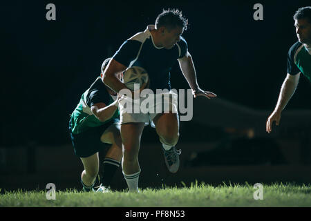 Flanker running with ball and tackling opponents during game. Rugby match in action. Stock Photo