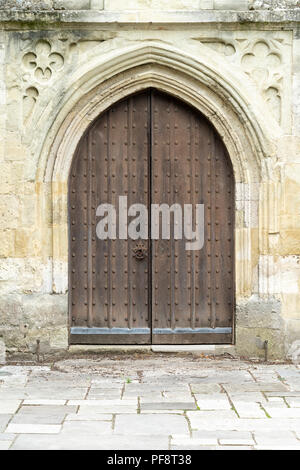 Studded church door set in old stone wall Stock Photo