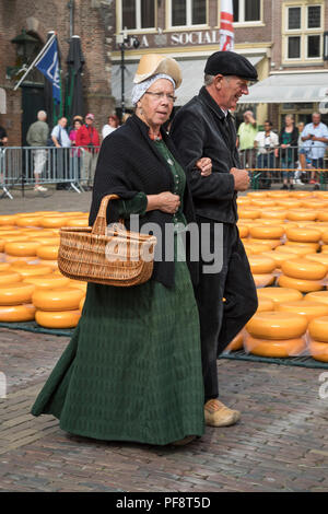 Alkmaar, Netherlands - June 01, 2018: Couple dressed in historical clothes walks on the cheese market before the opening Stock Photo