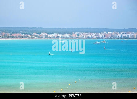 PALMA DE MALLORCA, SPAIN - JULY 14, 2012: Turquoise bay with windsurfers on a sunny summer day on July 14, 2012 in Mallorca, Spain. Stock Photo
