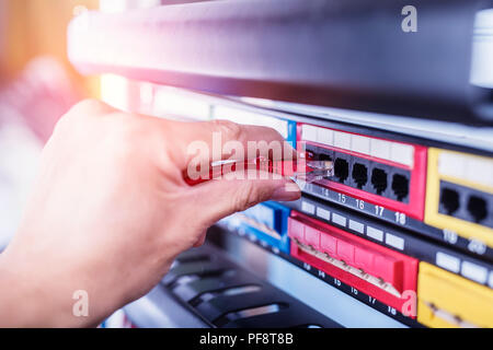 administrator holding network cables connected to servers Stock Photo