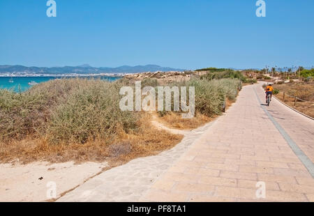 PALMA DE MALLORCA, SPAIN - JULY 21, 2012: Bicyclist in orange cycling along the track through coastal dry herb landscape on July 21, 2012 in Mallorca, Stock Photo