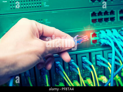 administrator holding network cables connected to servers Stock Photo