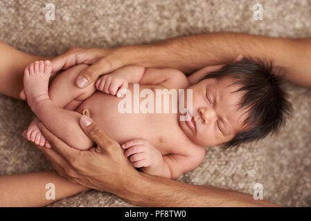 Parent taking care of newborn baby. Parents hands around small baby Stock Photo