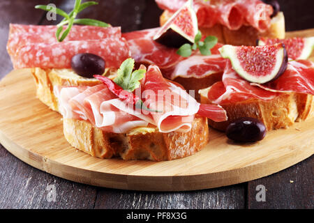 Sandwich with prosciutto or salami or crudo. Antipasti gourmet bruschetta snack Stock Photo