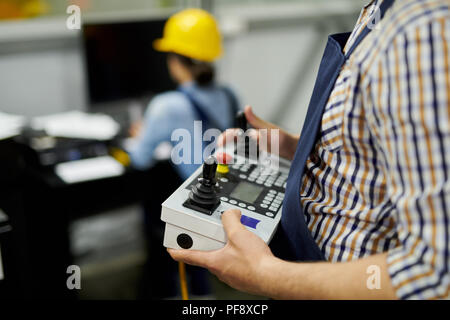Mid section shot of unrecognizable  factory worker operating machine unit pressing buttons on control panel, copy space Stock Photo