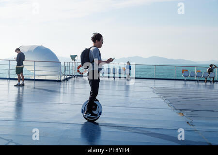 Tourist on a electric monowheel on deck of ferry from Jeju to Mokpo, South Korea Stock Photo