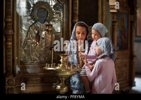 Young mother and her little blond Caucasian daughter with candles in Orthodox Russian Church Stock Photo