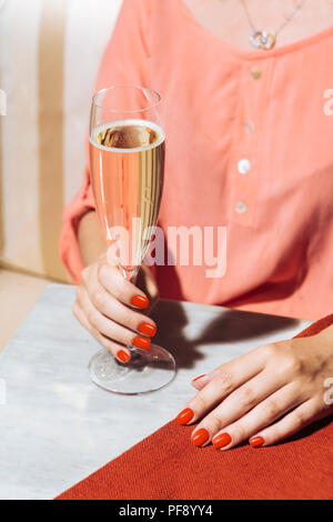 A glass of prosecco held by a girl in an elegant bar with vintage pop colors Stock Photo