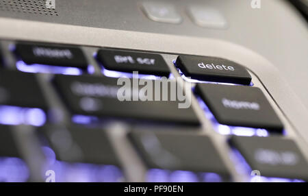 close up of  the delete symbol button tab on an illuminated laptop computer key board. The delete key Stock Photo