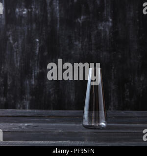 Transparent glass vase empty on a black wooden table, background. Stock Photo