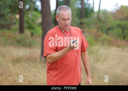 senior runner in nature with smart phone and earphones Stock Photo