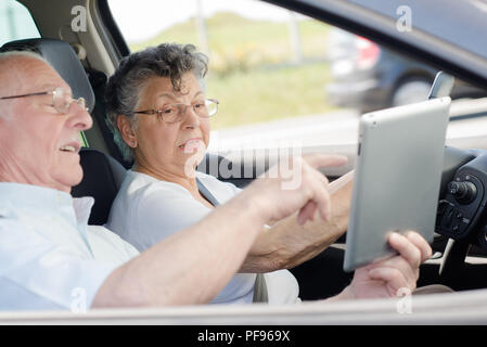 Elderly couple in car, looking at sat nav Stock Photo