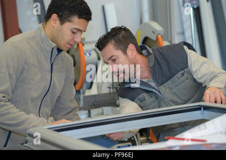 production smiling workers in coverall with different pvc window Stock Photo