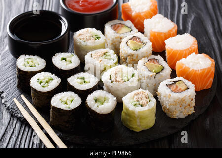 Japanese food: a menu of rolls with seafood close-up with sauces on a stone board. horizontal Stock Photo