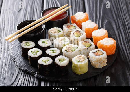 Sushi rolls set with sauces served on black stone slate on dark background. Horizontal Stock Photo