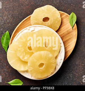 Dried pineapple rings on a brown table. Top viw of sweet paneapple slices. Stock Photo