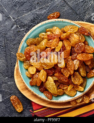 Yellow big raisins on black concrete background. Top view of dried grapes. Stock Photo