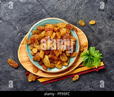 Yellow big raisins on black concrete background. Top view of dried grapes. Stock Photo