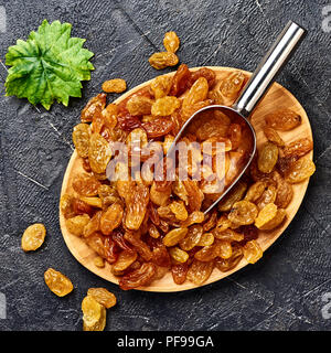 Yellow big raisins on black concrete background. Top view of dried grapes. Stock Photo