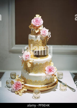 gold white pink tiered wedding cake with roses Stock Photo