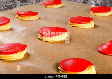 dough with red strawberry crumble for baking cakes shu eclairs on a parchment paper, classic french recipe, close-up Stock Photo