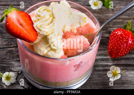 Strawberry Cheesecake Mousse Cup decorated by whipped cream and strawberry on an old rustic wooden table, studio lights, macro Stock Photo