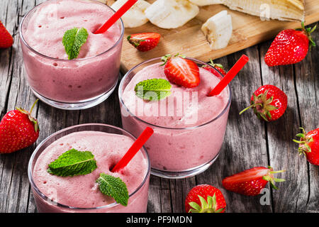 Strawberry Banana Smoothies Cups , slices of banana on a cutting board on an old rustic wooden table, studio lights, view from above, close-up Stock Photo