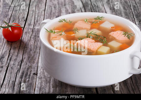 Hearty salmon soup on a white bowl ont a rustic wooden table close-up Stock Photo