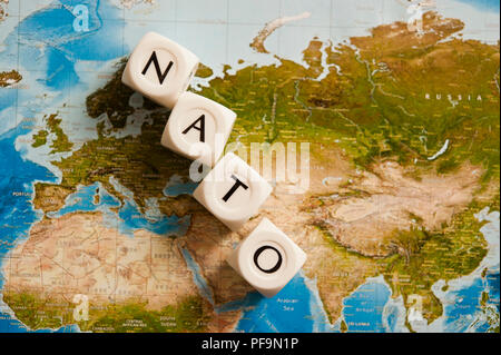 NATO spelled with dice on a world map, concept for the North Atlantic Treaty Organization expanding its members Stock Photo