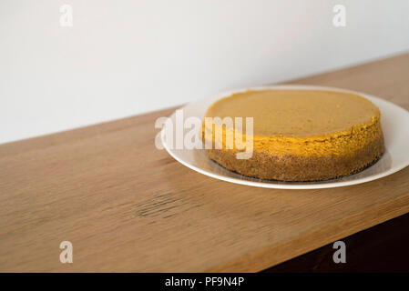 Whole Pumpkin Cheesecake Waiting on a Wooden Counter to Be Eatn Stock Photo