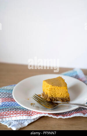 Half-Eaten Slice of Pumpkin Cheesecake on a Plate with a Fork Stock Photo