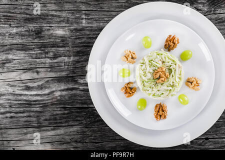 delicious a la carte salad with apples, celery and nuts, decorated with grapes on two white plates, view from above, blank space left, studio lighting Stock Photo