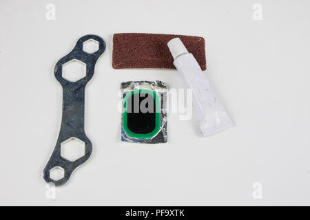 Bicycle tube, glue and patches in the workshop. Repairing a damaged wheel in a bike. Light background. Stock Photo