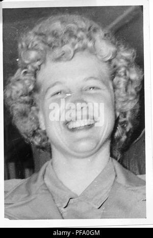 Black and white photograph, showing a headshot of smiling, young blonde woman, with her hair in ringlet curls, wearing military clothes, likely photographed during World War II, 1945. () Stock Photo