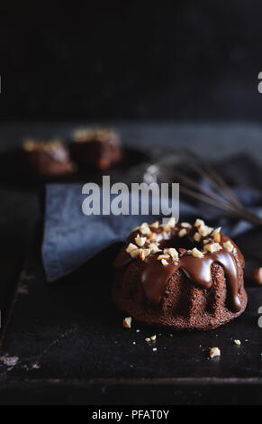 Mini chocolate bundt cakes topped with glaze and chopped hazelnuts Stock Photo