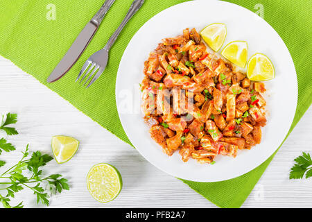 Braised Pig Ears or Oreja de Cerdo decorated with parsley on white dish with spices, chili pepper, slices of lime  on table mat, on wooden old boards, Stock Photo