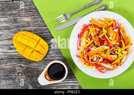 mango, bread crumbed chicken meat,  peanuts, bell pepper, red onion salad on white dish with half of  mango cutting in cubes, balsamic vinegar dressin Stock Photo