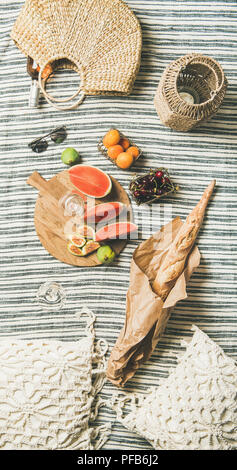 Rose wine, fresh fruit, baguette on blanket and straw bag Stock Photo